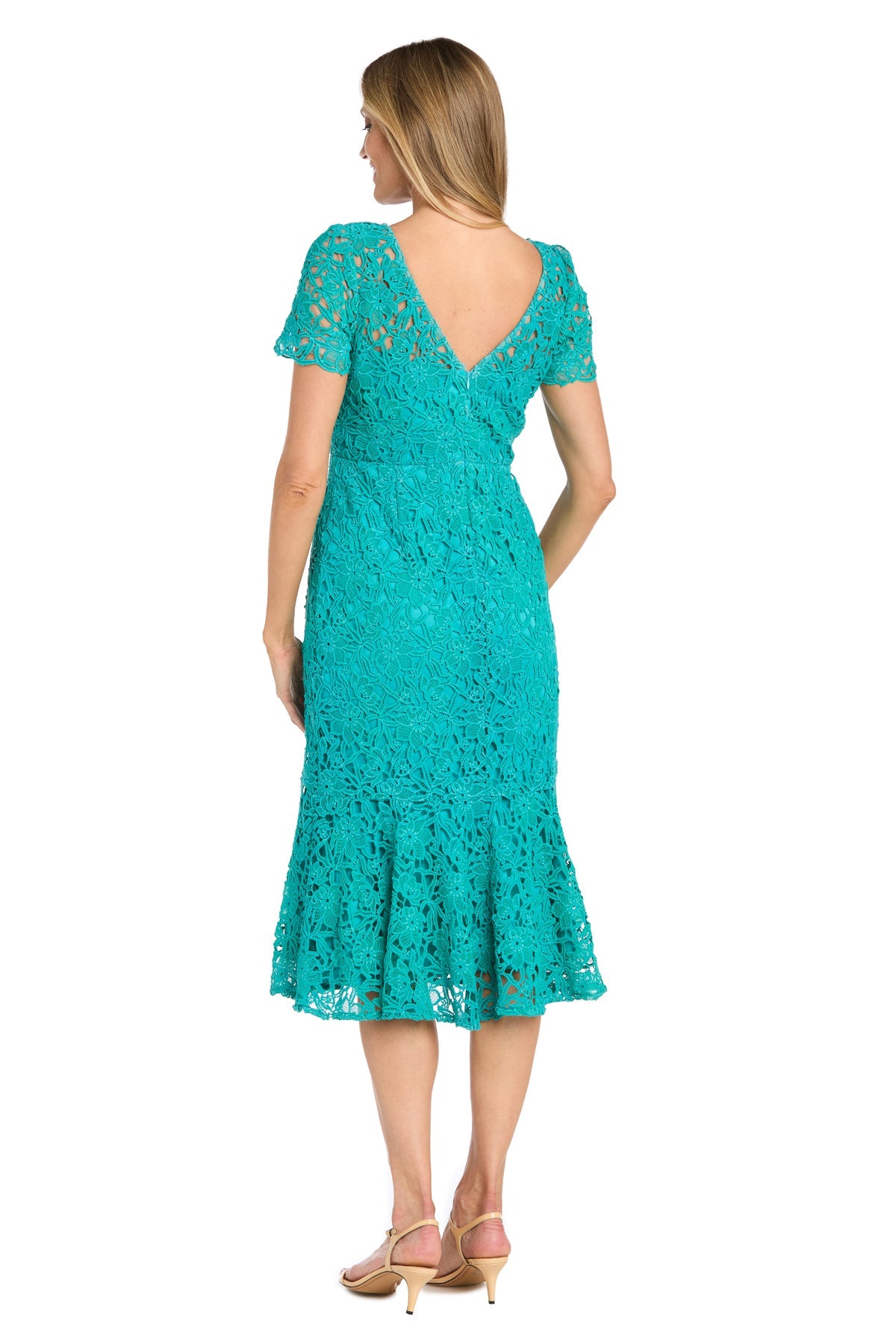 A woman faces away, modeling the R&M Richards 3498 Midi Lace Wedding Guest Dress in teal with short sleeves, a V-back, and ruffled hem, styled with beige heeled sandals.
